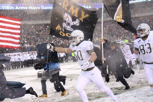 Army senior linebacker Bayle Wolf leads the Black Knights onto the field holding the American flag. (Photo by Steve Whitman/Military.com)