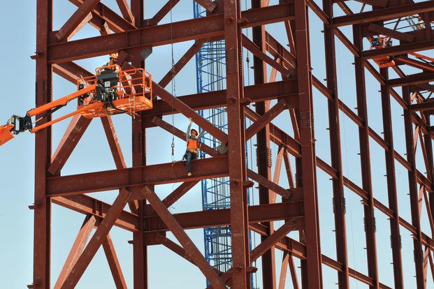 A steel worker fits beams. 