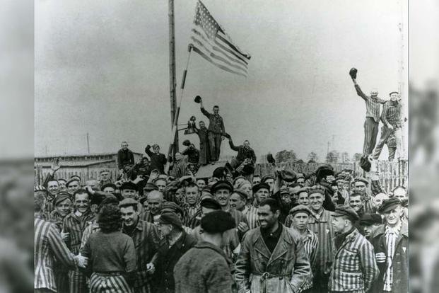 Former prisoners liberated from the Dachau Concentration Camp cheer at the raising of the Stars and Stripes, April 1945. (U.S. Army)