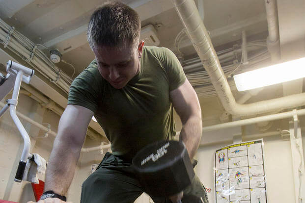 A Marine performs a dumbbell row.