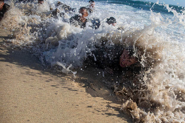 U.S. Marines are hit by waves while low crawling at Fort Hase Beach during a training exercise.