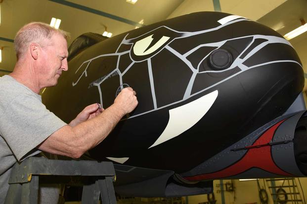 Air National Guard Paint Facility technician, Paul Grigsby cleans up stenciling on the nose of a U.S. Air Force A-10 Thunderbolt II while in the paint booth at the Sioux City, Iowa-based Air National Guard Paint Facility on June 29, 2021. The aircraft from the 122nd Fighter Wing has been painted with a non-standard paint scheme in order to commemorate the 100th anniversary of aviation in the Indiana National Guard. (U.S. Air National Guard photo: Senior Master Sgt. Vincent De Groot) Technician cleans up stenciling on the nose of an A-10 Thunderbolt II.
