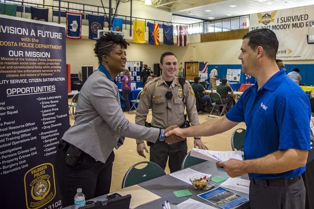 Sabrina Smith, sergeant detective for the Valdosta Police Department, shakes hands with Bart Larson, maintenance specialist for Hunt family housing, during the veterans career fair at Moody Air Force Base, Ga.