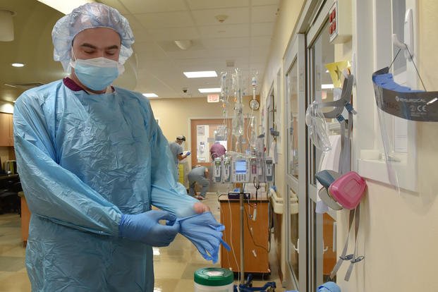 U.S. Air Force Maj. John Magulick, M.D., assigned to 59th Medical Wing, Joint Base San Antonio-Lackland, Texas, dons his personal protective equipment before entering a patient's room at the University Medical Center of El Paso, Texas.