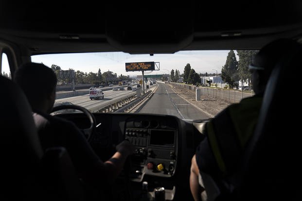 Accompanied by instructor Tony DeVeres from California Truck Driving Academy, right, student driver Edgar Lopez, 23, drives a practice truck along the freeway in Inglewood, Calif.