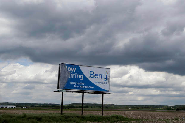 A weathered, ‘now hiring’ billboard stands along U.S. 40 near Lawrence, Kan.