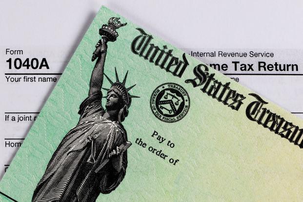 A check from the United States Treasury lies on top of a 1040 tax return form.