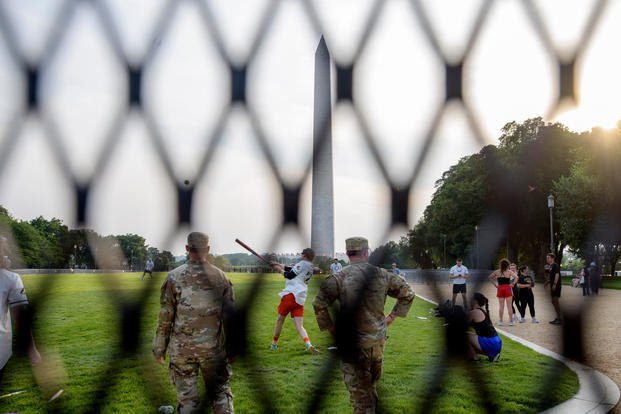 Seen through security fencing, Army Sgt. Chase Beasley, left, and Army Spc. Steven Holmes, right, sit-in on a game of softball with congressional staffers on the National Mall, during preparations for an upcoming military parade commemorating the Army's 250th anniversary and coinciding with President Donald Trump's 79th birthday, Thursday, June 12, 2025, in Washington. (AP Photo/Rod Lamkey, Jr.) Preparations for a military parade commemorating the Army's 250th anniversary