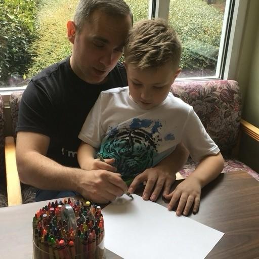 Juan Saro helps one of the boys he cares for with a drawing activity. The disabled Navy veteran says SNAP benefits are the only way to keep food on the table for his family. (Photo courtesy of Juan Saro)