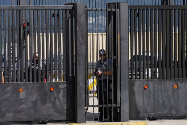 Security officers stand behind the main gate of the United States embassy in Caracas, Venezuela, Monday, Oct. 27, 2025. (AP Photo/Ariana Cubillos) Venezuela US Embassy