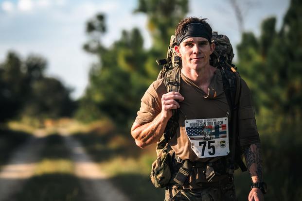 A U.S. Air Force Airman participates in the Norwegian Foot March at Tyndall Air Force Base, Florida, Oct. 9, 2025. Participants aimed to earn the Norwegian Foot March badge by completing the 18.6-mile ruck within their age bracket’s time limit while carrying a minimum of 24 pounds. (Senior Airman Zeeshan Naeem/U.S. Air Force) A service member wearing race number walks with a backpack.