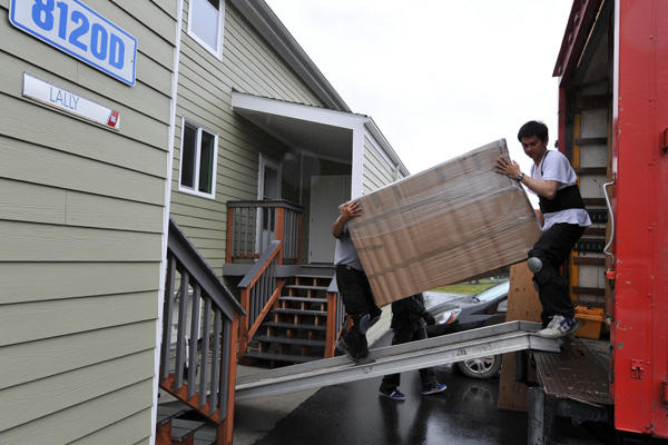 Two men loading furniture onto a moving truck.