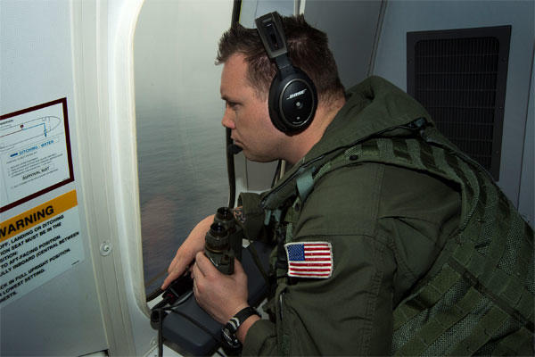 Chief Naval Aircrewman (Operator) Samuel Judd, assigned to Patrol Squadron (VP) 16, searches out the window of a P-8A Poseidon while flying over the Indian Ocean in support of the international effort to locate Malaysia Airlines flight MH370.