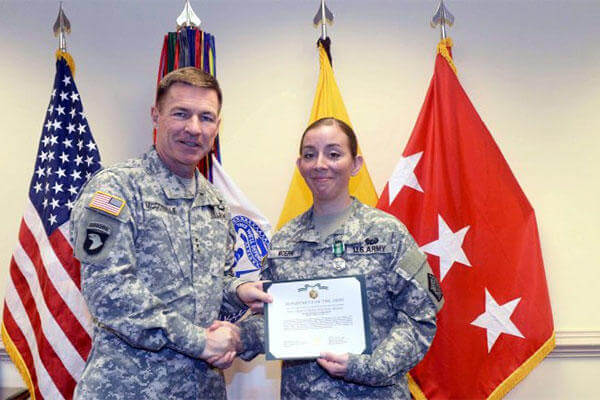 Lt. Gen. James C. McConville, the Army's deputy chief of staff for personnel, presents 1st Sgt. Katrina Moerk with the citation for her Army Commendation Medal. (U.S. Army Photo)