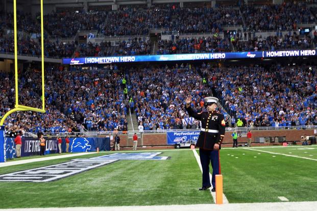 U.S. Marine Corps Sgt. Benjamin J. Annarino waves to more than 60,000 cheering fans during a Detroit Lions football game at Ford Field in Detroit, Oct. 20, 2015. (Photo by: Sgt. J. R. Heins)