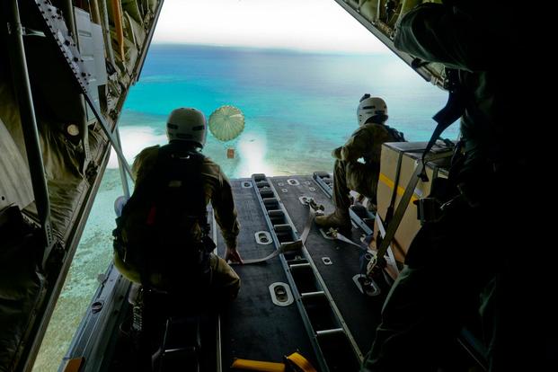 Australian Army Cpl. Teome Matamua and Sgt. Phillip McIllvaney, 176th Air Dispatch Squadron loadmasters, deliver the first bundle of Operation Christmas Drop 2015 to the island of Mogmog, Dec. 8, 2015. (Photo: Staff Sgt. Katrina Brisbin)