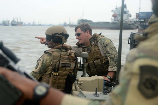 Lt. David Nartker, right talks with an Indonesian Naval Special Forces member while practicing small boat tactics during Cooperation Afloat Readiness and Training Indonesia 2015. (U.S. Navy photo/Joshua Scott)