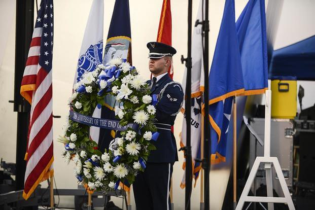 An Airman presents the wreath used in a wreath-laying ceremony. (Air Force photo/Tech. Sgt. Joshua L. DeMotts)