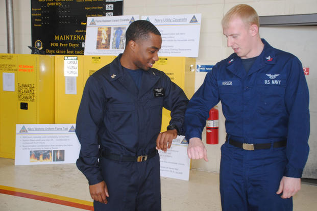 Operations Specialist 2nd Class Martin Vories compares the new flame-resistant variant  coverall with standard coveralls. (U.S. Navy photo by Melinda Larson)