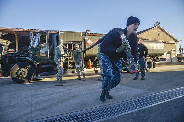 Petty Officer 3rd Class Christian Fakhoury, a Naval Air Field Atsugi Carrier Airborne Early Warning Squadron administrative assistant, pulls a fuel hose for daily inspection at Yokota Air Base, Japan. (U.S. Air Force/Senior Airman David Owsianka)