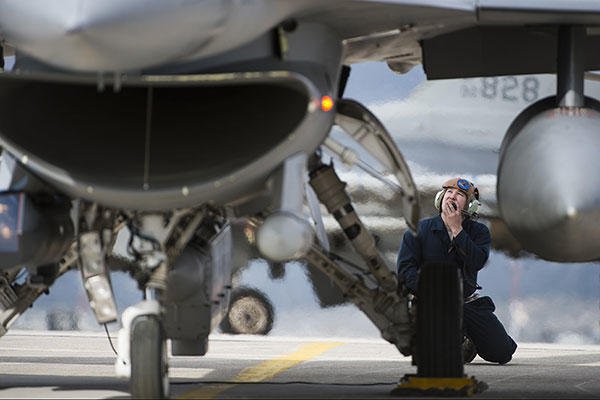 Staff Sgt. Ryan Anderson, a crew chief assigned to the 480th Expeditionary Fighter Squadron, performs preflight checks while communicating with an F-16 pilot before departure at Souda Bay, Greece. (U.S. Air Force/Staff Sgt. Christopher Ruano)
