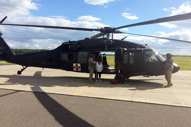 Crewmembers from the Wisconsin Army National Guard's Company F assist a dialysis patient from the Bad River Reservation in northern Wisconsin out of a UH-60 Black Hawk helicopter July 13, 2016. (Wisconsin National Guard photo)