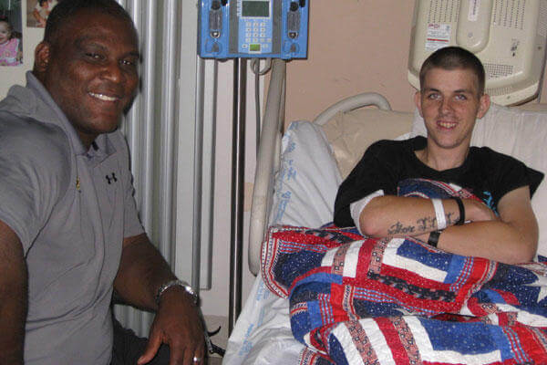 Col. Greg Gadson, director of the Army's Wounded Warrior Program, visits with Cpl. Jeremy D. Voels during a visit to the James A. Haley VA Hospital in Tampa.