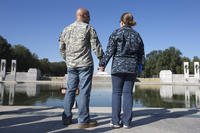 active duty sailor and her spouse, an Army veteran, hold hands during a rally at the National World War II Memoria