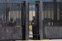 Security officers stand behind the main gate of the United States embassy in Caracas, Venezuela, Monday, Oct. 27, 2025. (AP Photo/Ariana Cubillos) Venezuela US Embassy