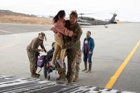 Alaska Air National Guard Tech. Sgt. Annie Kilborn, foreground, a C-17 Globemaster III loadmaster assigned to the 144th Airlift Squadron, 176th Wing, assists a child while evacuating approximately 300 displaced Alaskans out of Bethel, Alaska, Oct. 15, 2025 (Alaska National Guard photo by Staff Sgt. Joseph Moon, DVIDS).