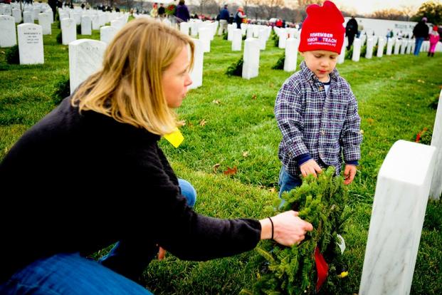 Volunteers place a wreath on a grave site during a National Wreaths Across America Day Ceremony at Arlington National Cemetery. (U.S. Air Force/Joseph Swafford)