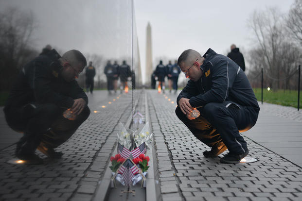 Master-at-Arms 1st Class Ian Barton reads a note left at the Vietnam Veterans Memorial during a run at the National Mall, April 9, 2018. (U.S. Navy photo/Stephen Hickok)