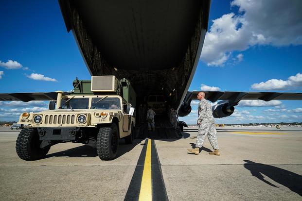 A soldier walks toward a Humvee equipped with an Airfield Lighting System that is about to be loaded into a U.S. Airforce C-17 Globemaster III. (U.S. Army/Private First Class Liem Huynh).