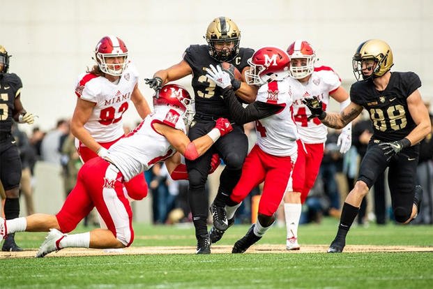 Darnell Woolfolk #33 of the Army Black Knights is tackled by two Miami Ohio Redhawks at West Point, october 20, 2018. (Photo from goarmywestpoint.com.)