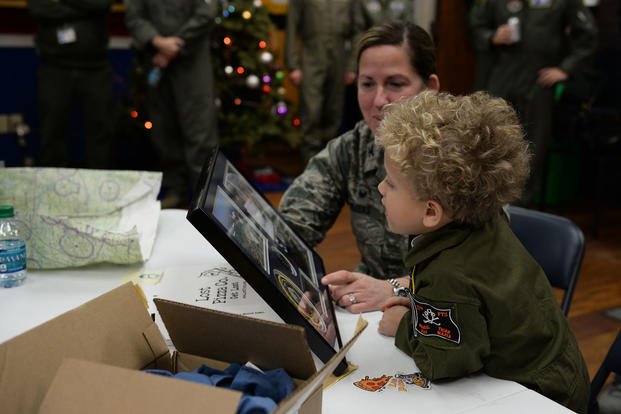 Tobias Taylor, Pilot for a Day, looks at a plaque of his hero shot and coin commemorating his time on base with Col. Samantha Weeks, 14th Flying Training Wing commander, Dec. 6, 2018, on Columbus Air Force Base, Mississippi. (U.S. Air Force/Hannah Bean)