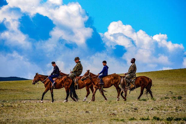 Marines ride horses with Mongolian youth at Five Hills Training Area, Mongolia, June 17, 2018, during Khaan Quest 18, a multinational exercise designed to strengthen international peace support capabilities. (U.S. Army photo by Sgt. Heidi Kroll)