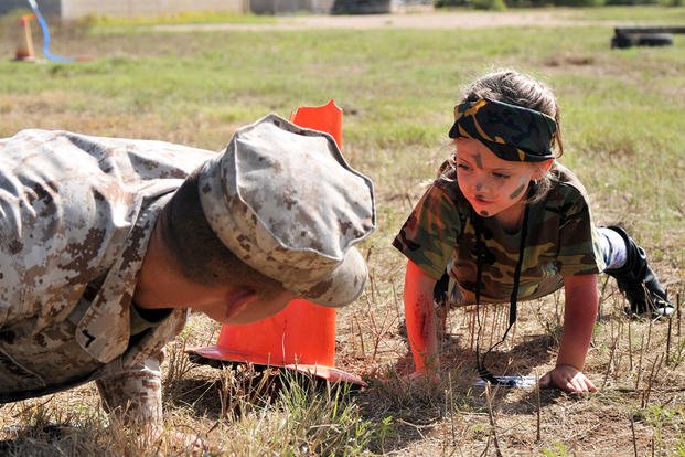 A child performs push-ups with a Marine during Operation Kids Investigating Deployment Services at Camp Sentinel on Goodfellow Air Force Base, Texas. (U.S. Air Force/Randall Moose)