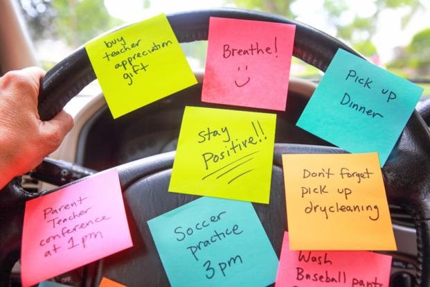 A steering wheel is decorated with post it notes with reminders.