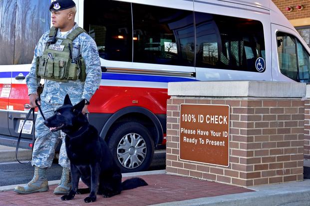 Senior Airman Clifton Giles, 11th security support squadron military working dog handler, and his dog, Jerry, stand at the main gate as a show of force on Joint Base Andrews, Maryland, March 12, 2019. Giles and Jerry occasionally stand at the front gate to deter possible threats to the base. (Noah Sudolcan/U.S. Air Force)