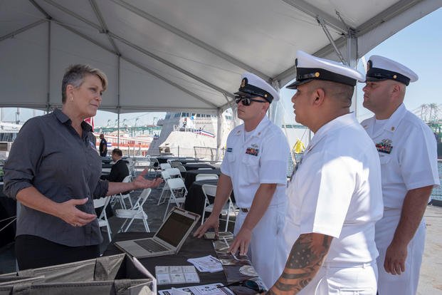 Sailors speak with a woman about jobs. 