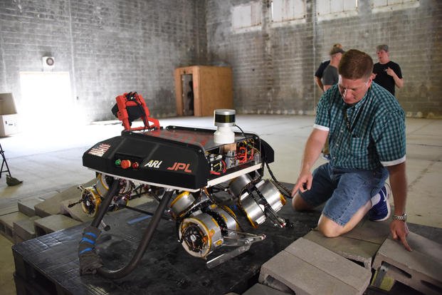 Mechanical Engineer Jason Pusey inspects actuators on a robotic dog prototype called LLAMA during an experimental integration event. (Image courtesy CCDC Army Research Laboratory)