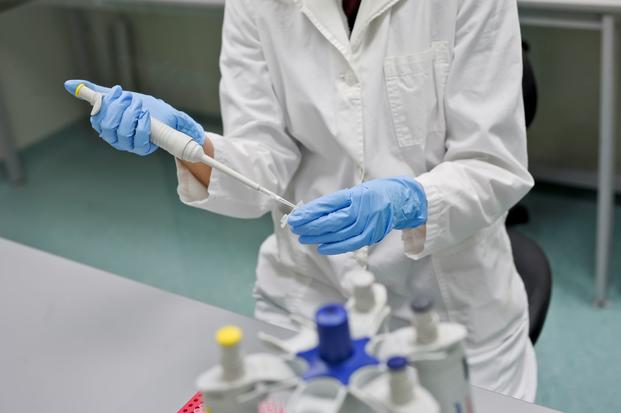 A lab associate in blue gloves performing a DNA test. (Source: Getty Images)
