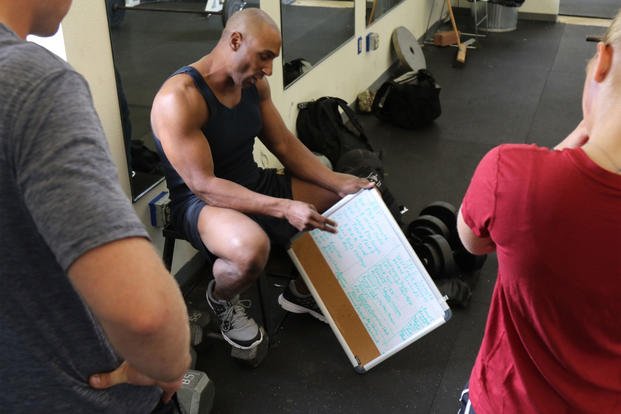 Sgt. 1st Class Marcus Wallace; 504th Military Intelligence Brigade; Fort Hood Texas; explains his work out routine to Spc. Wes Schroeder (left) and Spc. Hanna Baker. (U.S. Army/Melissa N. Lessard)