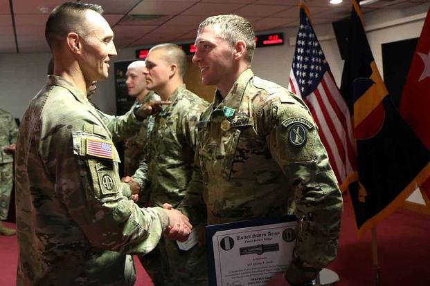 Command Sgt. Major Timothy Guden, CSM for Training and Doctrine Command, congratulates Sgt. Michael Smith on earning the Expert Soldier Badge at Joint Base Langley-Eustis on Nov. 21, 2019. Staff Sgt. Joseph Hansen (center) and Capt. David Morin (end) also earned the ESB. Matthew Cox/Military.com