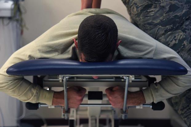 An airman lies on a table for a back treatment.