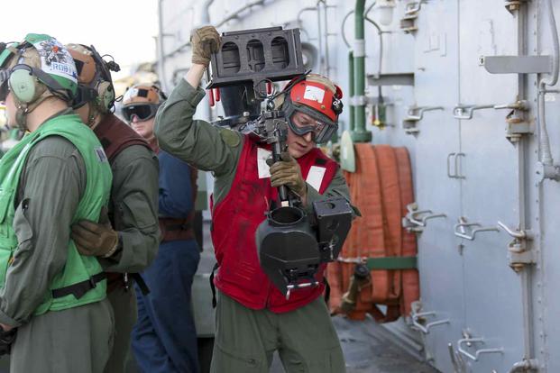 Cpl. Kevin Reimer carries a machine gun mount aboard the amphibious assault ship USS Bataan.