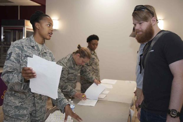 Tech. Sgt. Candace Gonzalez hands out surveys to an Individual Ready Reservist during a muster on Joint Base Andrews, Maryland, Aug. 19, 2017 