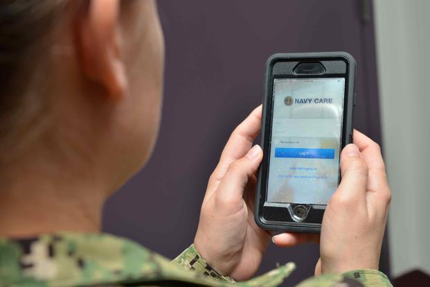A sailor uses the Navy Care app on her cell phone for a virtual health visit.