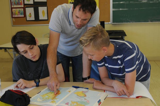 teacher and students looking at atlas