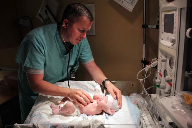 A pediatrician gives a newborn a quick listen to her heartbeat during a routine checkup.